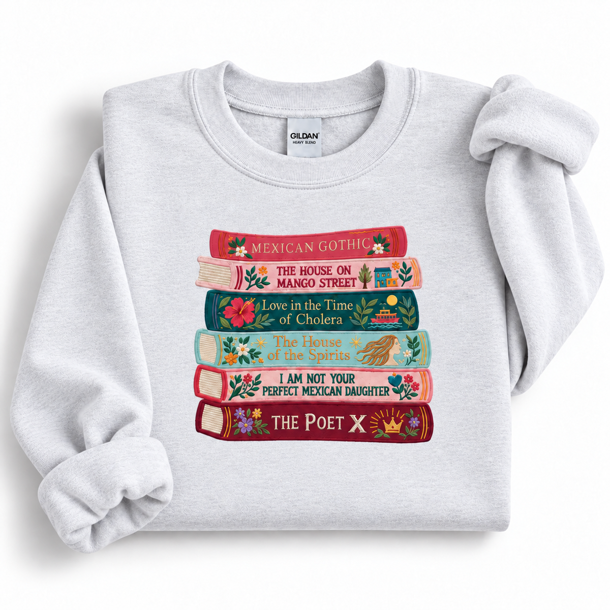 Ash gray Gildan 18000 sweatshirt featuring colorful embroidered book spines inspired by Latina and Latin American literature.