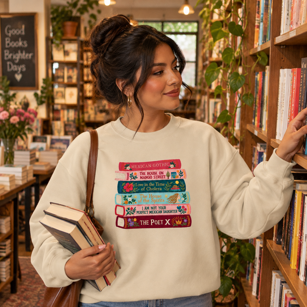 Woman wearing a cream embroidered Latina literature book stack sweatshirt while browsing books in a cozy bookstore.