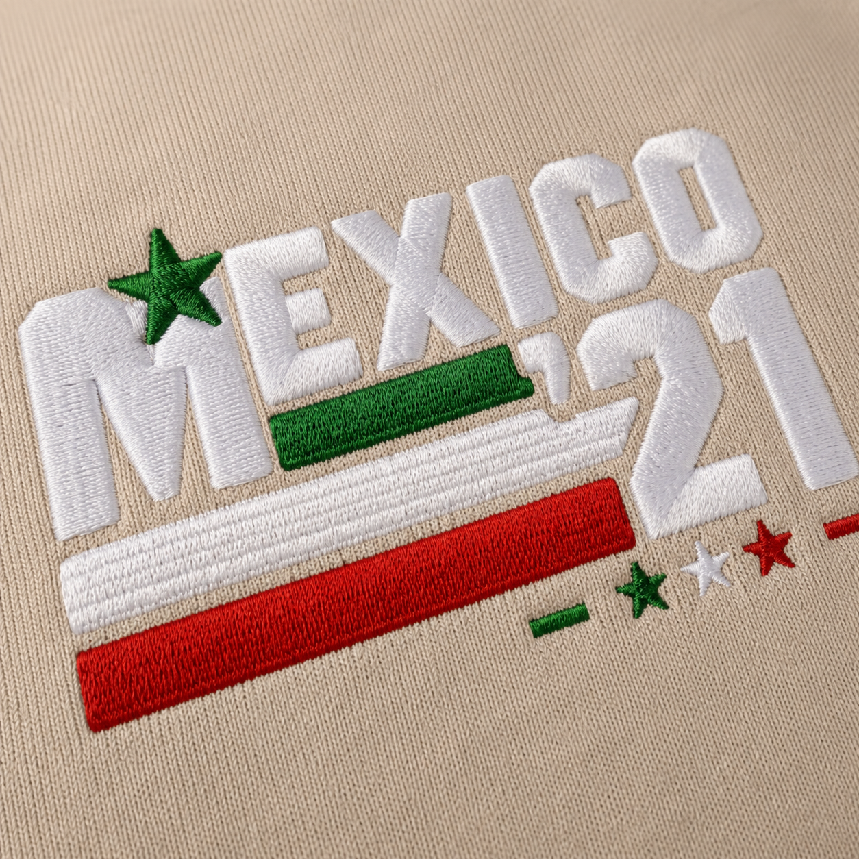 Close-up of Embroiderzilla's retro Mexico '21 embroidered design on a sand Gildan Heavy Blend crewneck sweatshirt, showcasing premium satin stitch embroidery and thread texture.